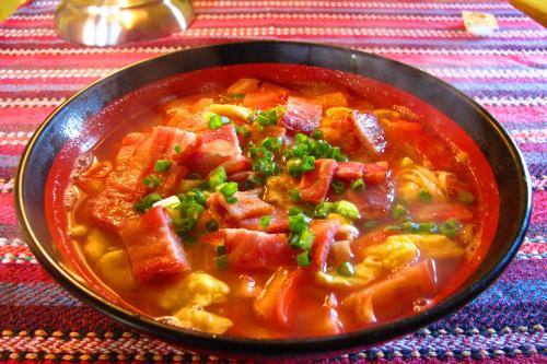 a bowl of soup with meat and vegetables on a table at Kevin's Trekker Inn in Shangri-La