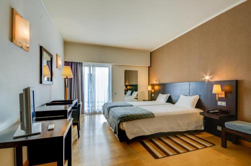 a hotel room with a bed and a desk and a television at Hotel Alvorada in Estoril
