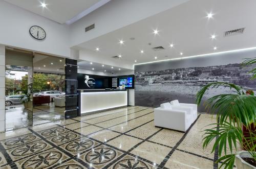 a lobby with a white couch and a clock at Hotel Alvorada in Estoril