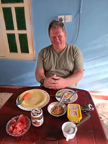a man sitting in front of a table with food at Nilaveli Beach Rooms in Nilaveli