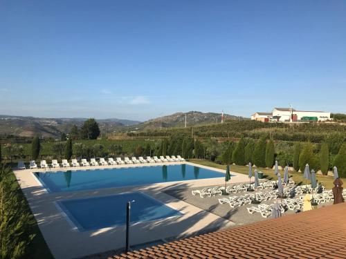 a pool with chairs and umbrellas at Quinta do Atoleiro in Lamego