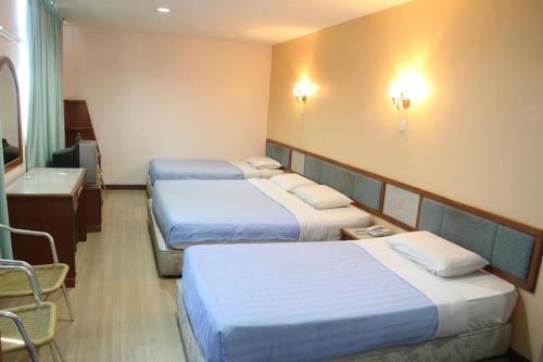 um quarto de hotel com três camas e uma casa de banho em Monaco Dynasty Hotel em Tawau
