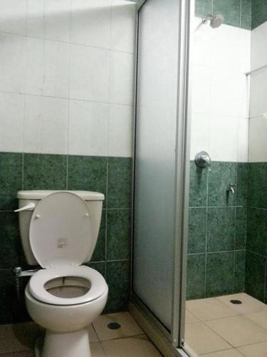 a bathroom with a toilet and a shower at Monaco Dynasty Hotel in Tawau