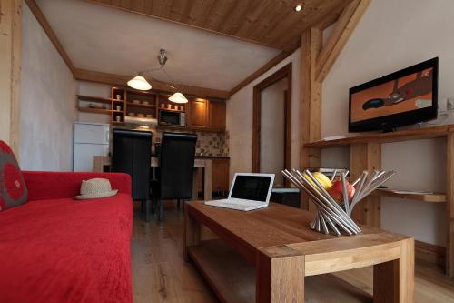 a living room with a red couch and a laptop on a wooden table at Chalet des Neiges : La Cime Des Arcs in Arc 2000
