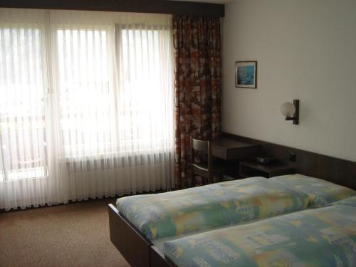 a bedroom with a bed and two large windows at Hotel Eden Sisikon in Sisikon