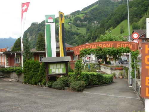 a sign in front of a resort with a mountain at Hotel Eden Sisikon in Sisikon