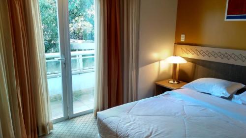 um quarto com uma cama e uma grande janela em Flat no Hotel Mountain Village em Canela