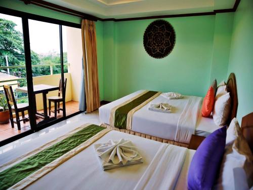 a hotel room with two beds and a balcony at Baan SS Karon in Karon Beach