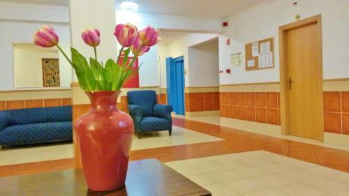 a red vase with pink flowers sitting on a table at Rialgarve in Faro