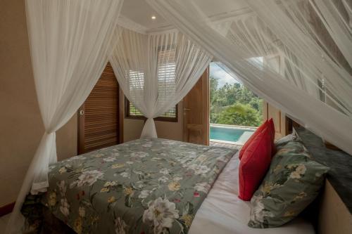 ein Schlafzimmer mit einem Himmelbett und einem Fenster in der Unterkunft Villa Tepi in Ubud