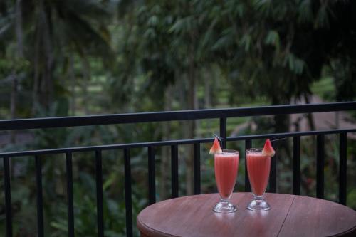 deux verres de boissons roses posés sur une table en bois dans l'établissement Puri Astina Villa, à Ubud