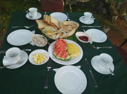 a table topped with white plates and bowls of food at Sigiri Forest View in Sigiriya