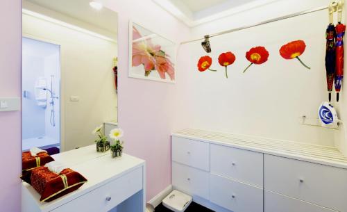 a room with white cabinets and red flowers on the wall at Baan Sandao by Nanni in Hua Hin