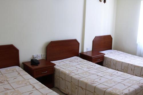 a room with three beds and two tables at Kasgar Court Hotel in Karaoğlanoğlu