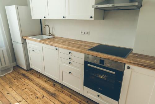 a kitchen with white cabinets and a sink and a stove at Krastmala in Liepāja