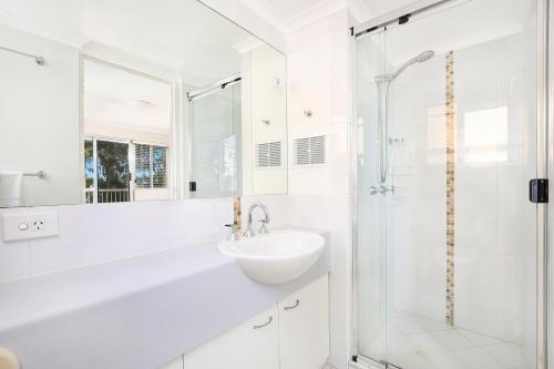 a white bathroom with a sink and a shower at Belvedere Apartments in Caloundra