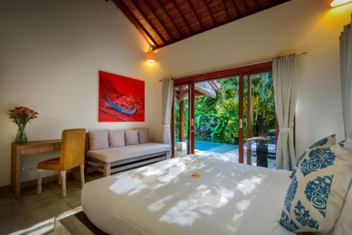 a bedroom with a bed and a desk and a couch at Villa Vastu Seminyak in Seminyak