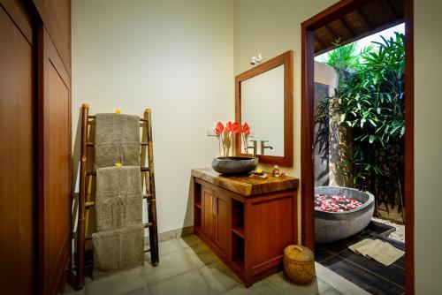 a bathroom with a tub and a sink and a mirror at Villa Vastu Seminyak in Seminyak