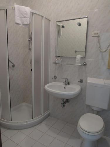 a bathroom with a shower and a toilet and a sink at Hotel Stella Maris in Grado