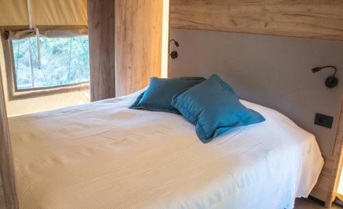 łóżko z niebieską poduszką na górze w obiekcie Anfasteröd Gårdsvik - Tälten w mieście Ljungskile