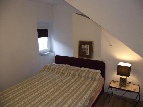 a bedroom with a bed and a lamp and a window at Apartments Dobrinj in Dobrinj