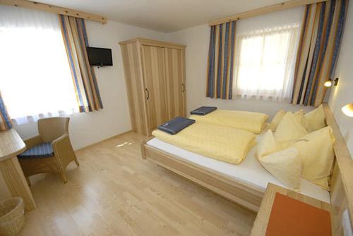 a bedroom with a bed with yellow sheets and a desk at Appartements Stiererhof in Ramsau am Dachstein