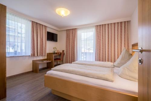 een slaapkamer met een groot bed in een kamer met ramen bij Villa Volgger in Mayrhofen