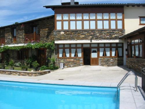 a house with a swimming pool in front of a building at Hotel O Forno in Salcedo