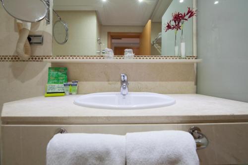 a bathroom with a sink and a mirror and towels at Silken Luis de León in León