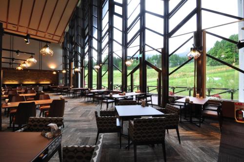 a restaurant with tables and chairs and large windows at Hachimantai Mountain Hotel & Spa in Hachimantai