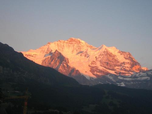 a mountain with the sun shining on it at Hotel Bellevue - Traditional Swiss Hideaway in Wengen
