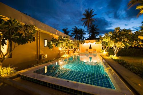 a swimming pool in the backyard of a house at night at Villa Na Pran, Pool Villa in Pran Buri