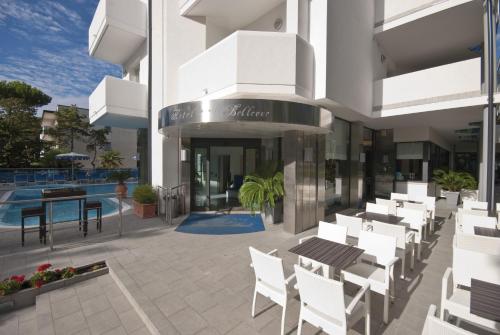 a patio with white chairs and tables on a building at Hotel Bellevue in Lignano Sabbiadoro
