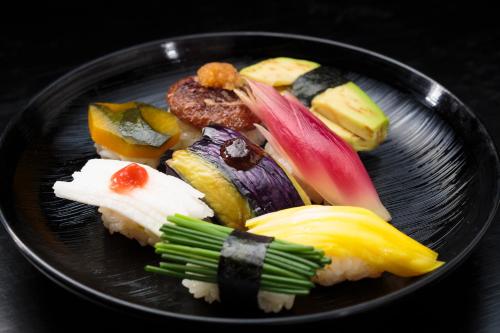 a black plate of food with sushi on it at Hakkei in Maniwa