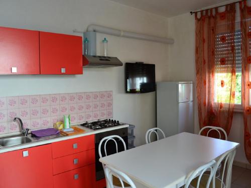 a kitchen with red cabinets and a white table at Casa Vacanze Manila in Marina di Mancaversa