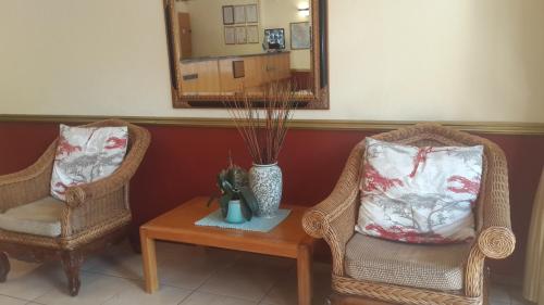 two chairs and a table with a mirror and a vase at Marlot Guest House in Polokwane