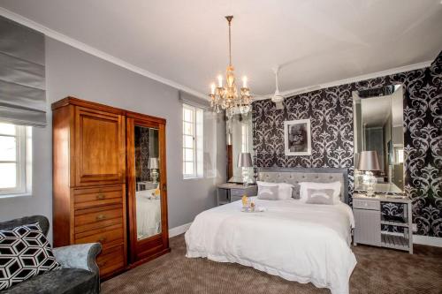 a bedroom with a large white bed and a chandelier at The Villa Rosa Hotel & Self-catering Apartments in Cape Town