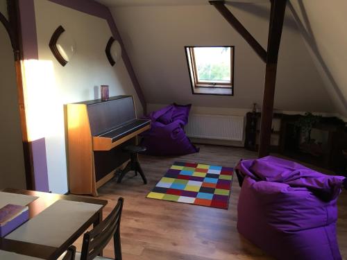 ルンブルクにあるApartman Adeleのピアノと紫の枕が備わるリビングルーム