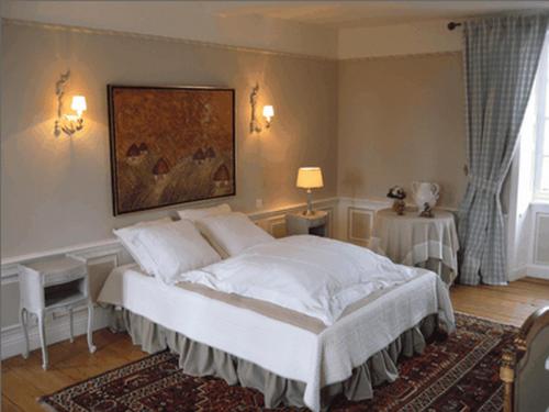 a bedroom with a white bed with a painting on the wall at Chambres d'Hôtes Le Petit Sully in Sully
