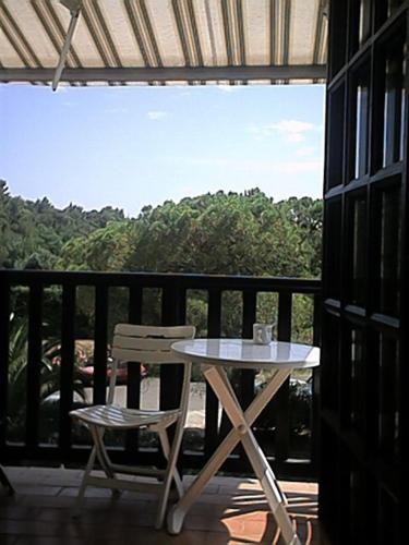 une table et une chaise assises sur une terrasse couverte dans l'établissement Residence Lou Cigaloun, à La Croix-Valmer