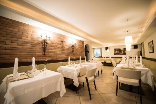 a restaurant with white tables and chairs and a brick wall at Hotel Condor in San Vigilio Di Marebbe