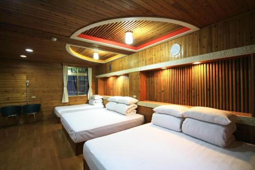 a room with four beds in a wooden room at Gemlu in Lugu