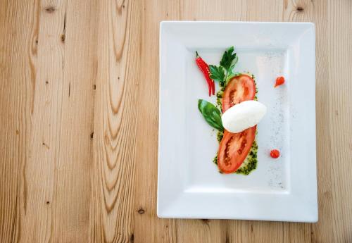 a white plate with food on a wooden table at Hotel Condor in San Vigilio Di Marebbe