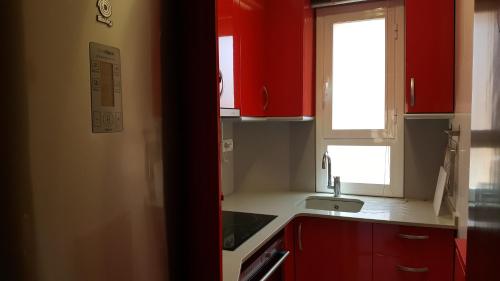 a kitchen with red cabinets and a sink and a window at Caputxins Apartment in Tarragona
