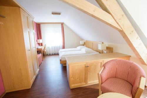 デッゲンハウザータールにあるランガストホフ リンデのベッド、デスク、椅子が備わる屋根裏部屋です。