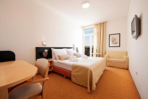 a hotel room with a bed and a table and chairs at Radenci Spa Resort - Sava Hotels & Resorts in Radenci