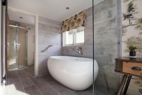 a white bath tub sitting under a window in a bathroom at Mill End Hotel in Chagford
