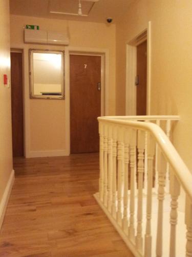 a hallway with a white staircase and a door at The Dharma Lodge in Enfield