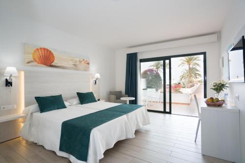 a bedroom with a large white bed with a green blanket at Hotel THB Flora in Puerto del Carmen