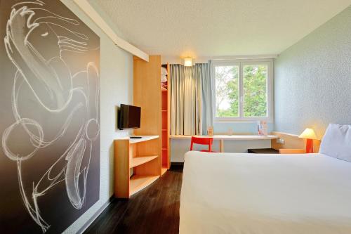 ポワティエにあるイビス ポワティエ ボーリューのベッドとデスクが備わるホテルルームです。